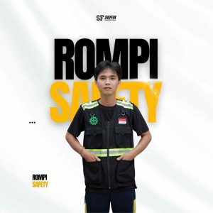 Seorang pria mengenakan rompi safety (safety vest) berwarna hitam dengan strip reflektif kuning-hijau, logo K3 di dada kanan, dan bendera Merah Putih di dada kiri, berlatar belakang desain grafis bertuliskan "ROMPI SAFETY"